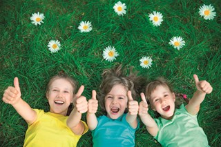 Kinderen in gras met duim omhoog